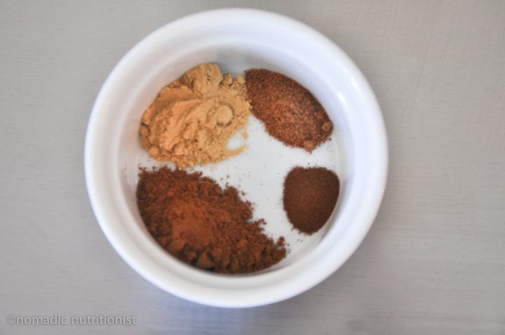 A white ramekin with spices for pumpkin spice blend.