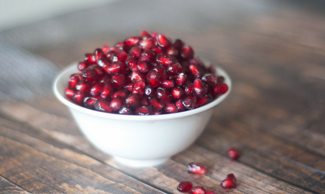 Pomegranate seeds in white bowl