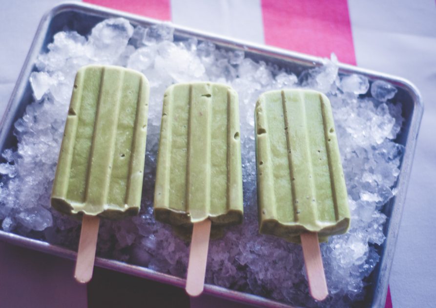 3 Avocado Match Popsicles on a tray filled with ice