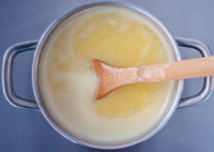 A saucepan with melted butter and a wooden spoon