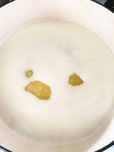 A saucepan with butter cooking on low heat and foam rising to the top