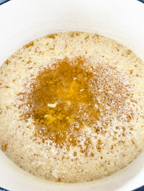 A saucepan with clarified butter cooking on low heat and milk solids separating
