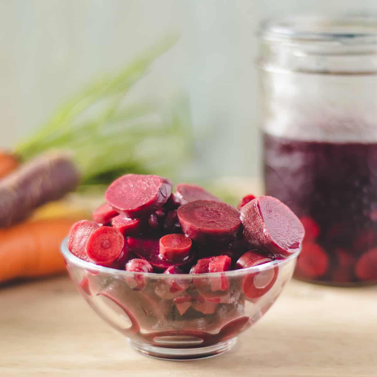 A small glass bowl of slices of lactofermented purple carrots.