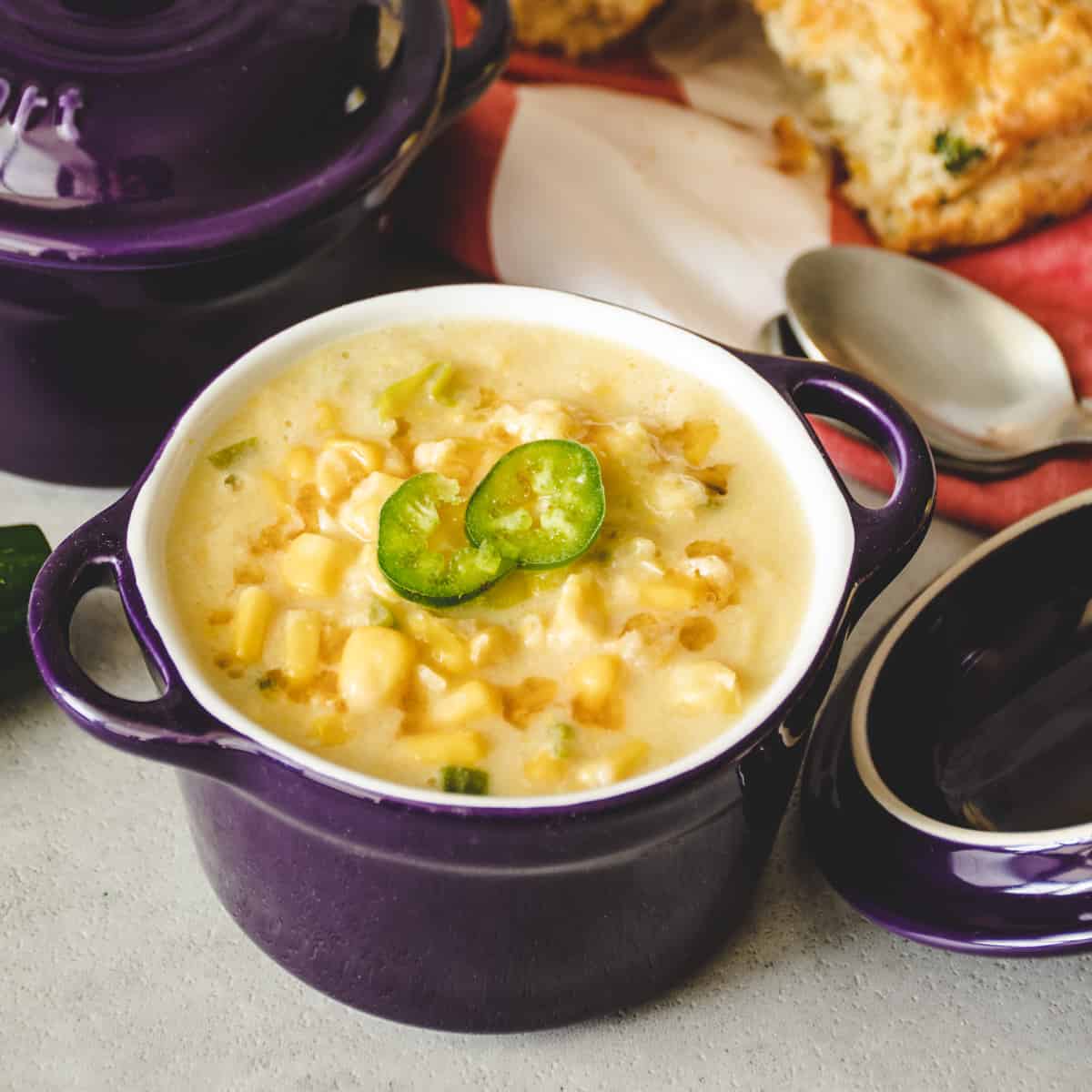 Chinese Trinidadian corn soup topped with sliced jalapenos in a small purple soup bowl.