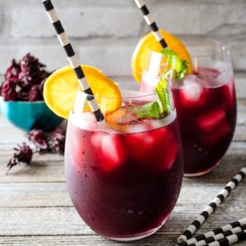 Two glasses of iced sorrel with an orange slice.