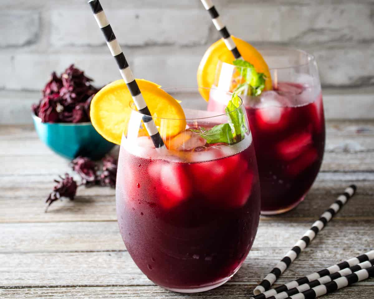 Two glasses of iced sorrel with an orange slice.