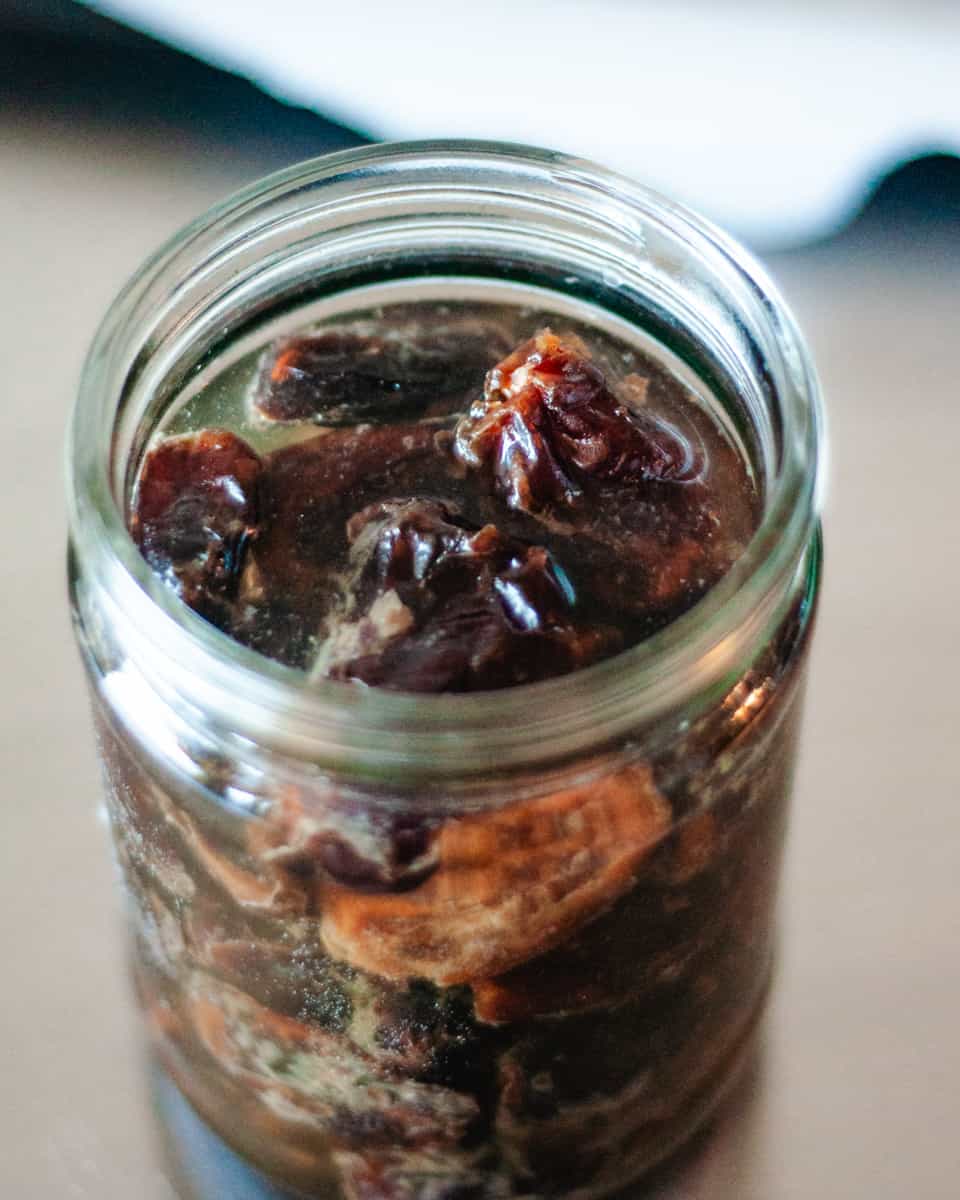 An overhead shot of dates soaking in a small jar of water.