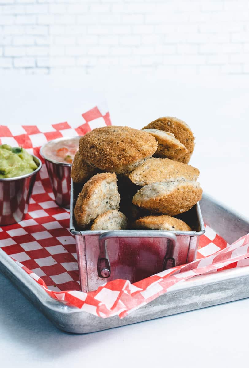 Blue Corn Madeleines stacked in a small metal dish on a red & white checkered cloth.