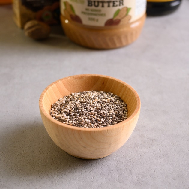 A small wooden bowl with black and white chia seeds.
